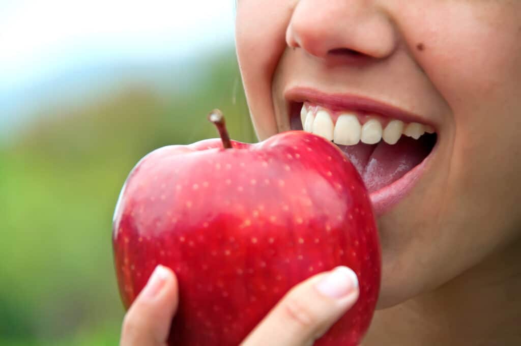 Paciente de Roger Dental con buena salud oral comiendo una manzana